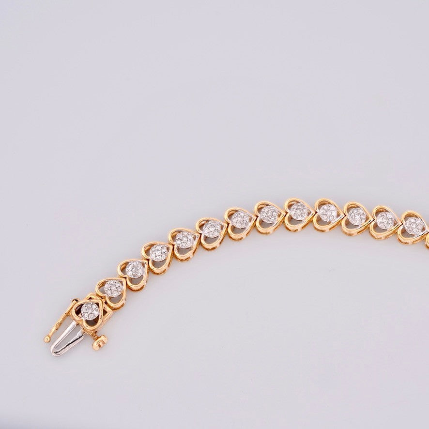 Gemmas Jewelry Edit 10k yellow gold tennis bracelet with heart-shaped links adorned with diamond clusters.